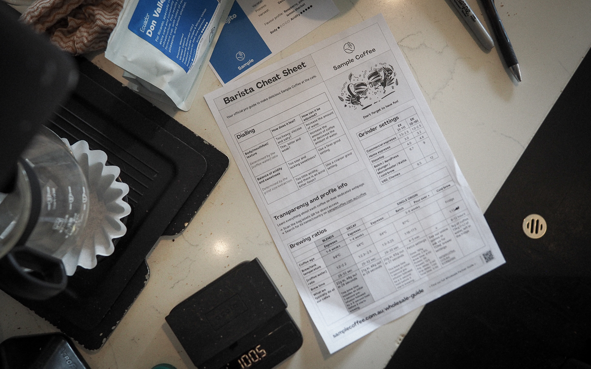 Our barista cheatsheet or professional guide lying flat on the cafe counter, amongst other brewing gear.