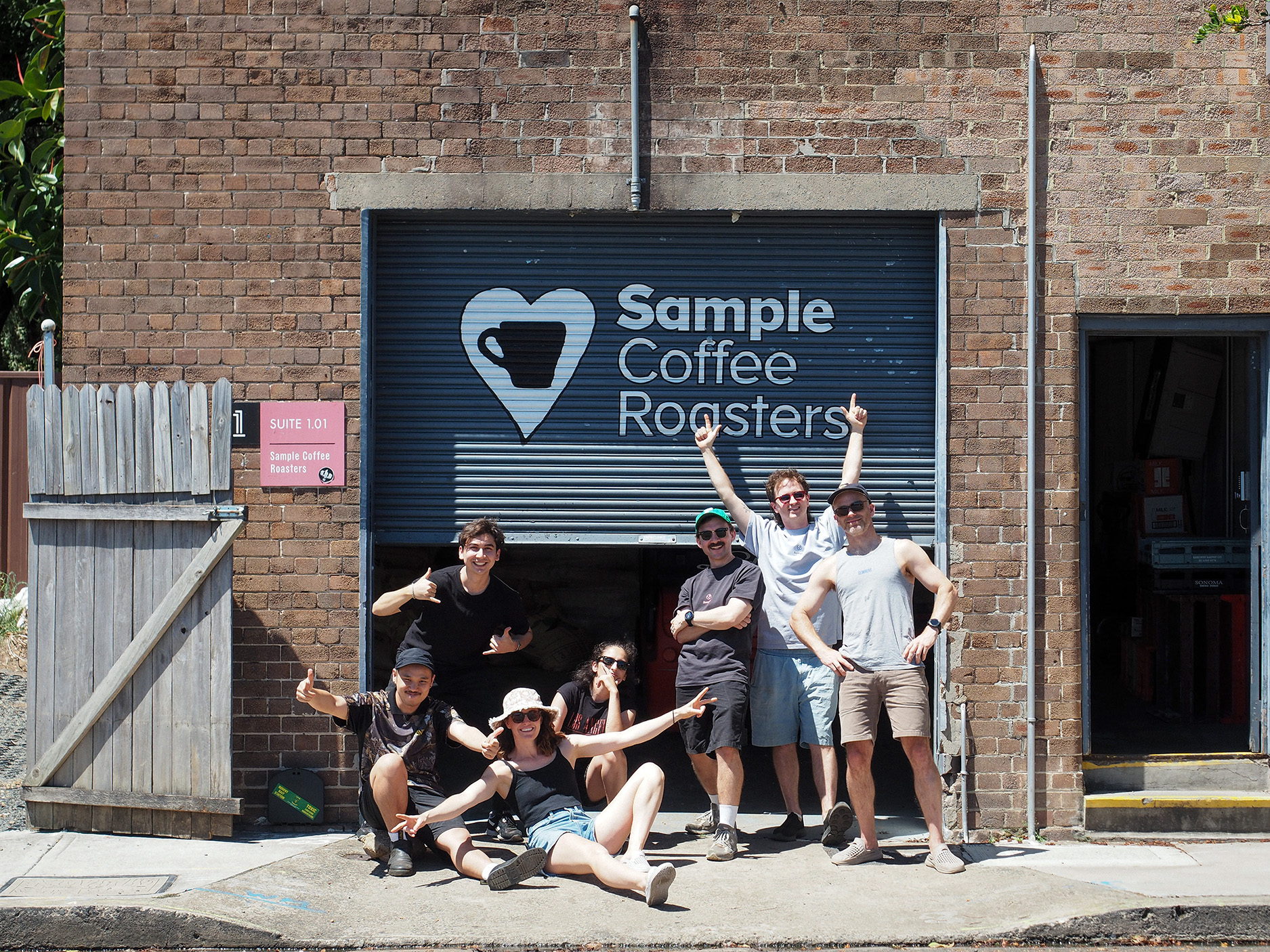 Most of the Sample Coffee team in the last working day of 2025, in front of our roastery roller door.